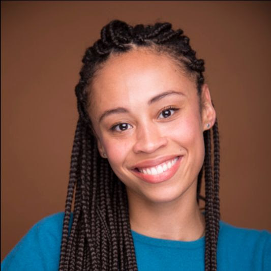 Development Fellow Mykel Nairne is an African-American woman with her hair in long, dark brown braids. She is wearing a turquoise top and is smiling at the camera.