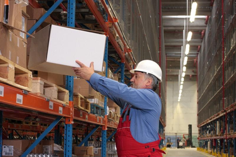 A warehouse worker lifts a box,