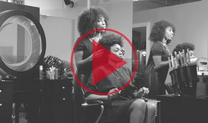 Black women at a salon respond to a man in a suit that tells the hair stylist to straighten their hair?