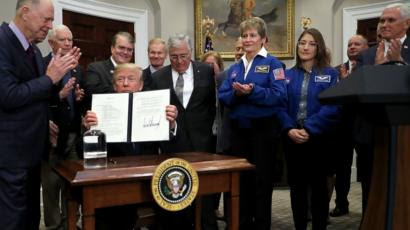 U.S. President Donald Trump holds up "Space Policy Directive 1" after signing it during a ceremony.