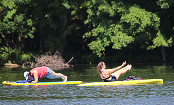 two women doing exercises on stand-up paddleboards in the water