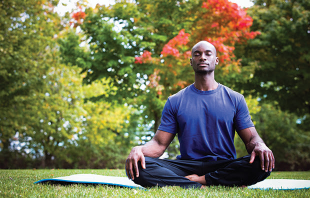 A man meditating outdoors.