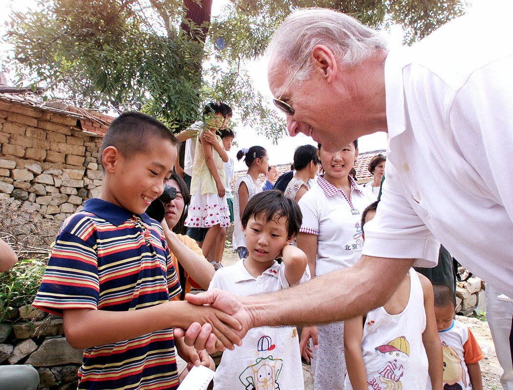 2001年，拜登访问燕子口村，与7岁的高山（音）握手。