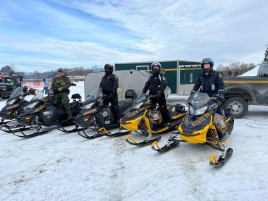Ranger and law enforcement lined up on snowmobiles 