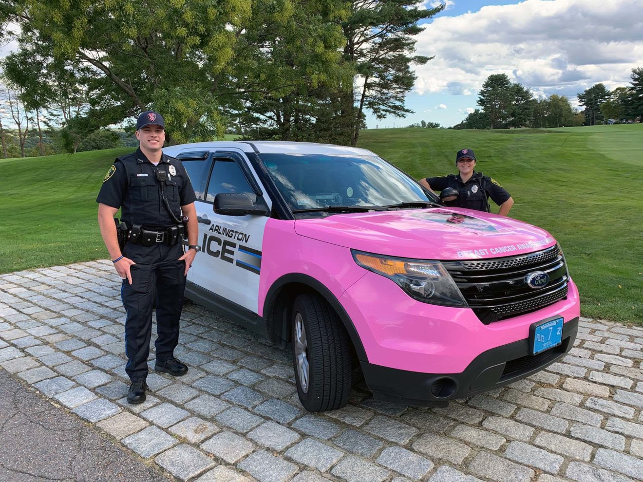 Officer Brandon Whalen and Officer Salena Zona stand with the Arlington Police Department cruiser painted pink to raise awareness of breast cancer for Breast Cancer Awareness Month in October. (Photo Courtesy Arlington Police Department)