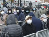 Patients wear personal protective equipment while maintaining social distancing as they wait in line for a COVID-19 test at Elmhurst Hospital Center, Wednesday, March 25, 2020, in New York. Gov. Andrew Cuomo sounded his most dire warning yet about the coronavirus pandemic Tuesday, saying the infection rate in New York is accelerating and the state could be as close as two weeks away from a crisis that sees 40,000 people in intensive care. Such a surge would overwhelm hospitals, which now have just 3,000 intensive care unit beds statewide. (AP Photo/John Minchillo)