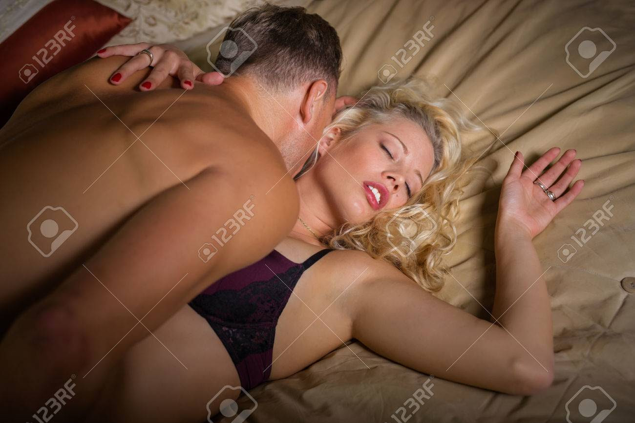 Man on top of woman kissing her neck  in bedroom - 65575173