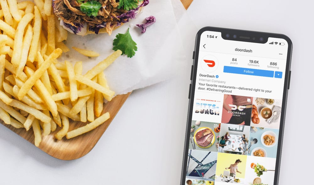 DoorDash app open on a phone next to food DoorDash app open on a phone next to food
