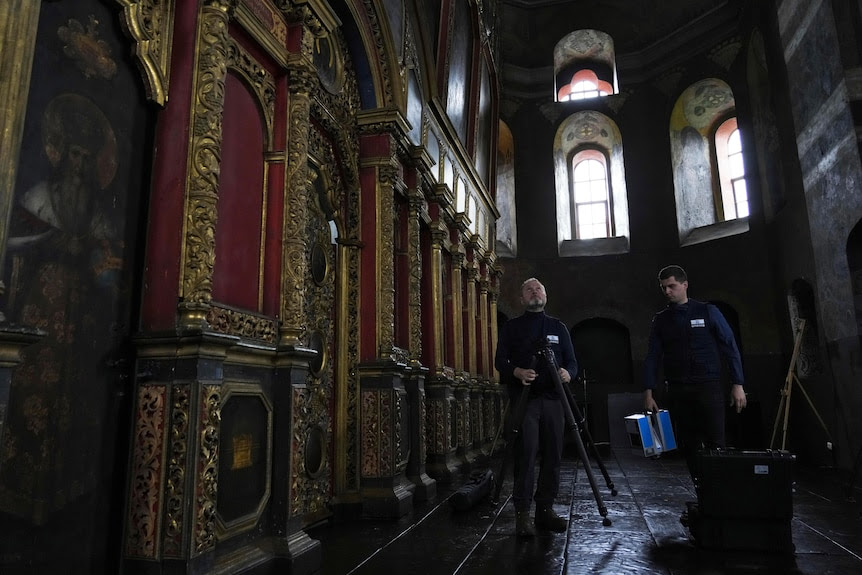 Two volunteers set an imager up on a tripod to scan the walls of the All Saints Church in Kyiv, Ukraine.