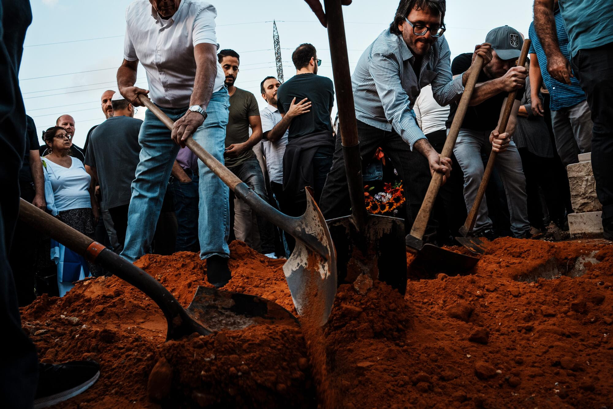 Michael Levy, centro derecha, se une a otros para ayudar a enterrar a su hermano Daniel Levy.