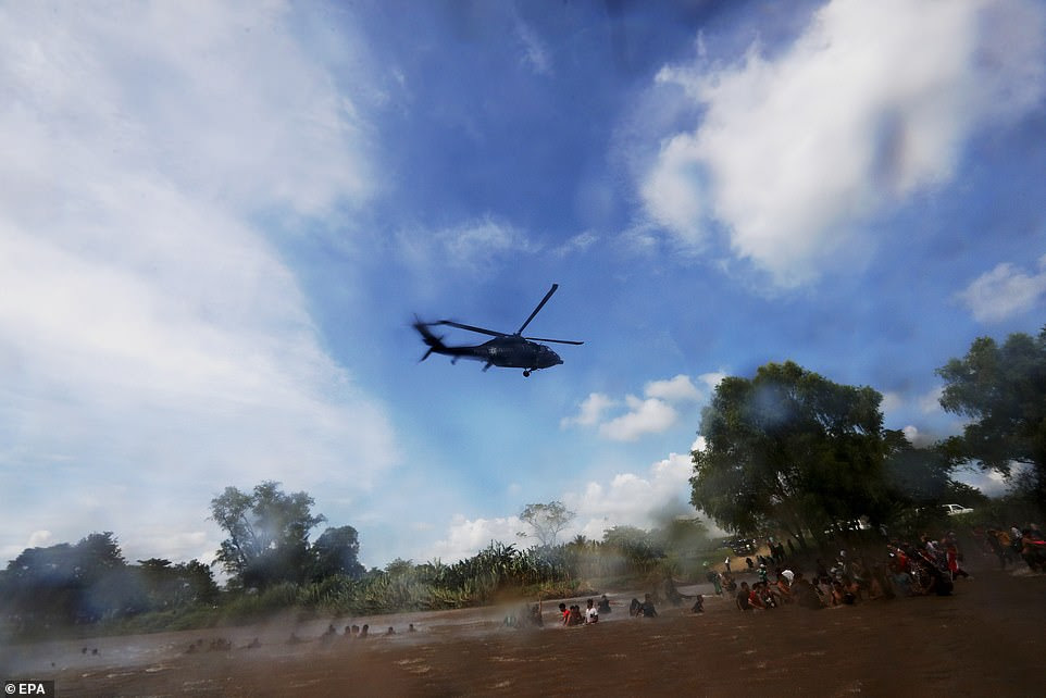 A helicopter of the Mexican Police flies over members of the second migrant caravan, mostly Hondurans, as they cross the Suchiate River