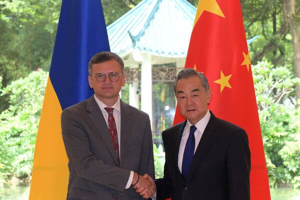 Two men shake hands in front of the flags of Ukraine and China.