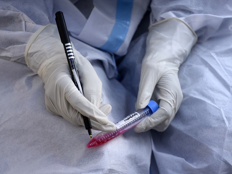 A health worker writes name of a person on a tube after collecting swab sample for COVID-19 test, India.