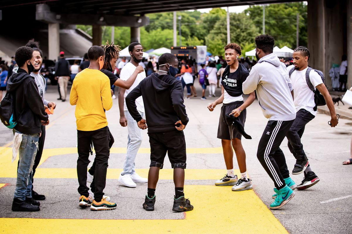 A circle of young men laughing near Black Wall Street
