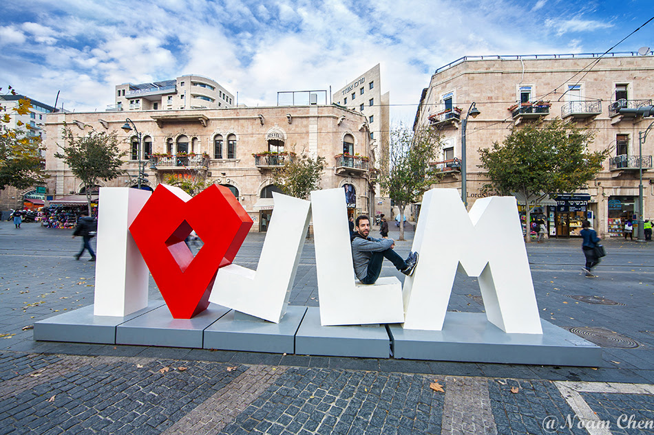 man sitting on the i love sign in jerusalem street