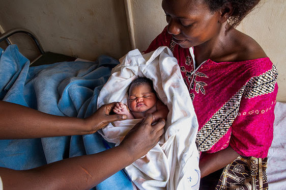 Photo of a mother and baby, and a nurse holding the baby's fingers