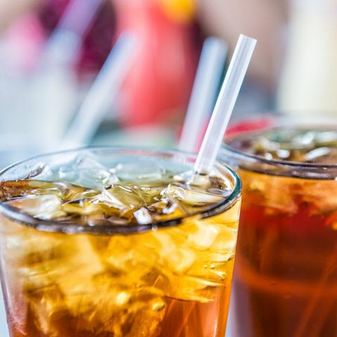Macro closeup of iced tea or soda with ice cubes and straw in glass