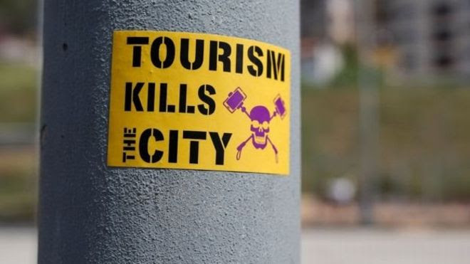 'O turismo mata a cidade', diz um adesivo colado em um poste, em Barcelona