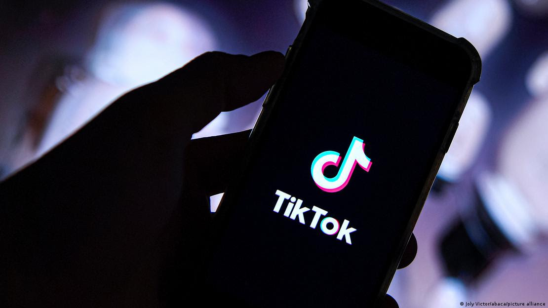 Mão segura smartphone com logo do Tiktok