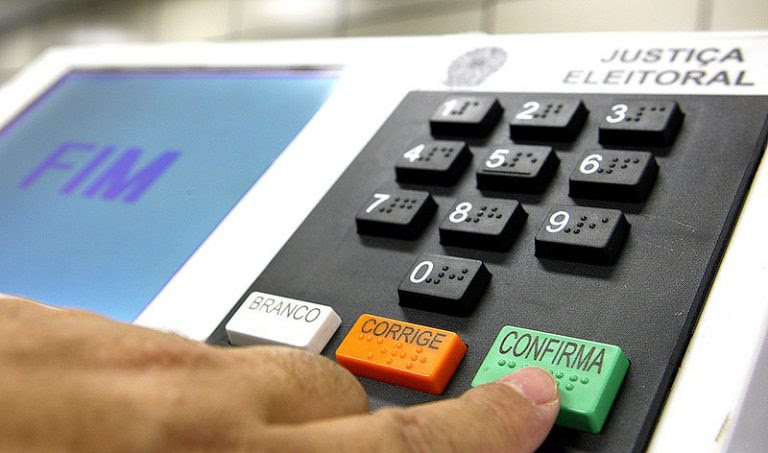 Pessoa aperta a tecla onde está escrito "Confirma" na urna eletrônica