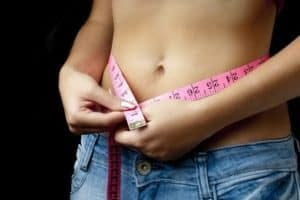 Woman with measuring take around belly