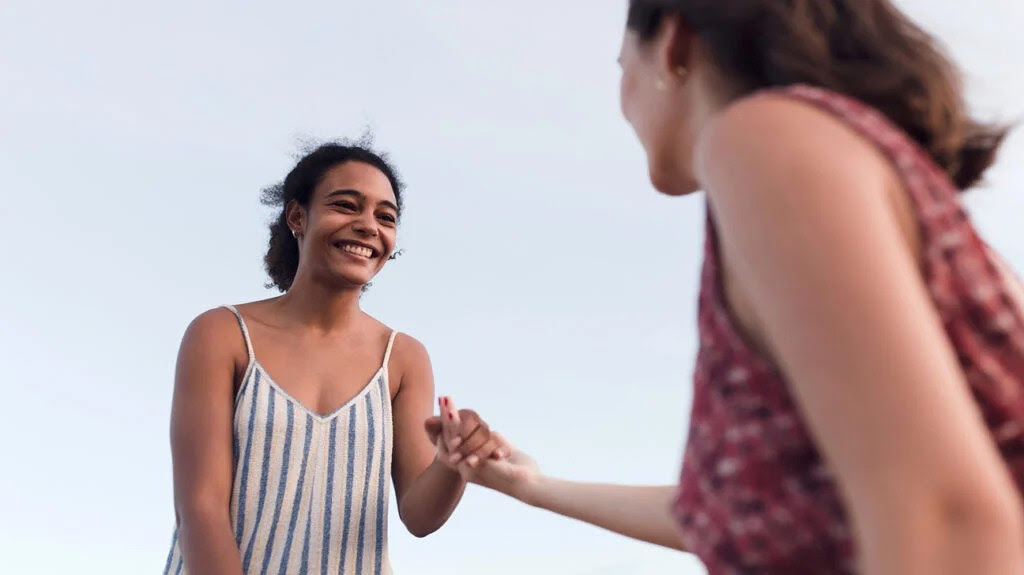 A female holding a female friend's hand.