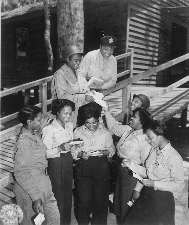 Black and white photograph of a group of women nurses gathering together reading letters.