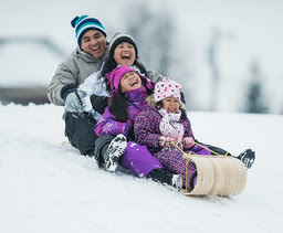 two adults and two children sledding on a toboggan