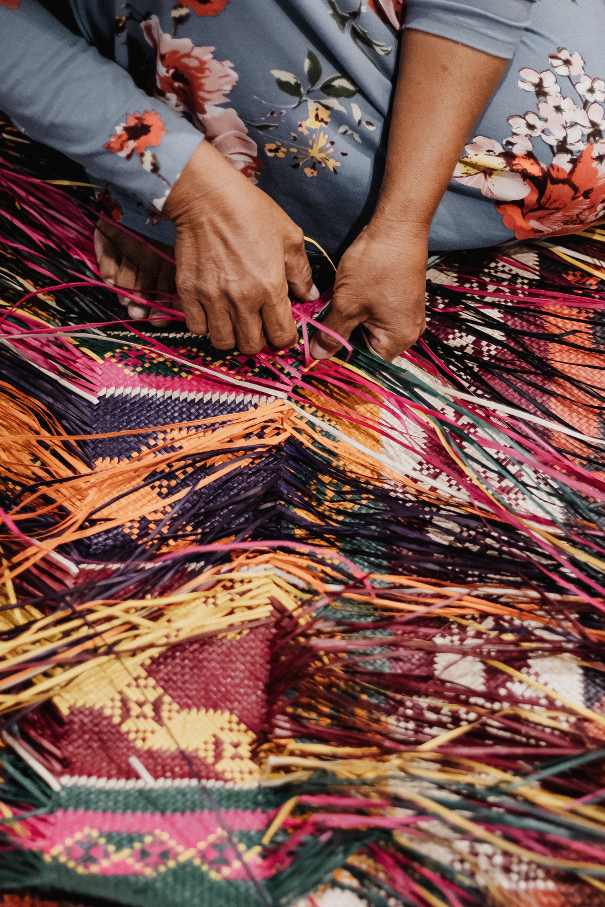 Many colored fibers being woven together into a traditional pattern.