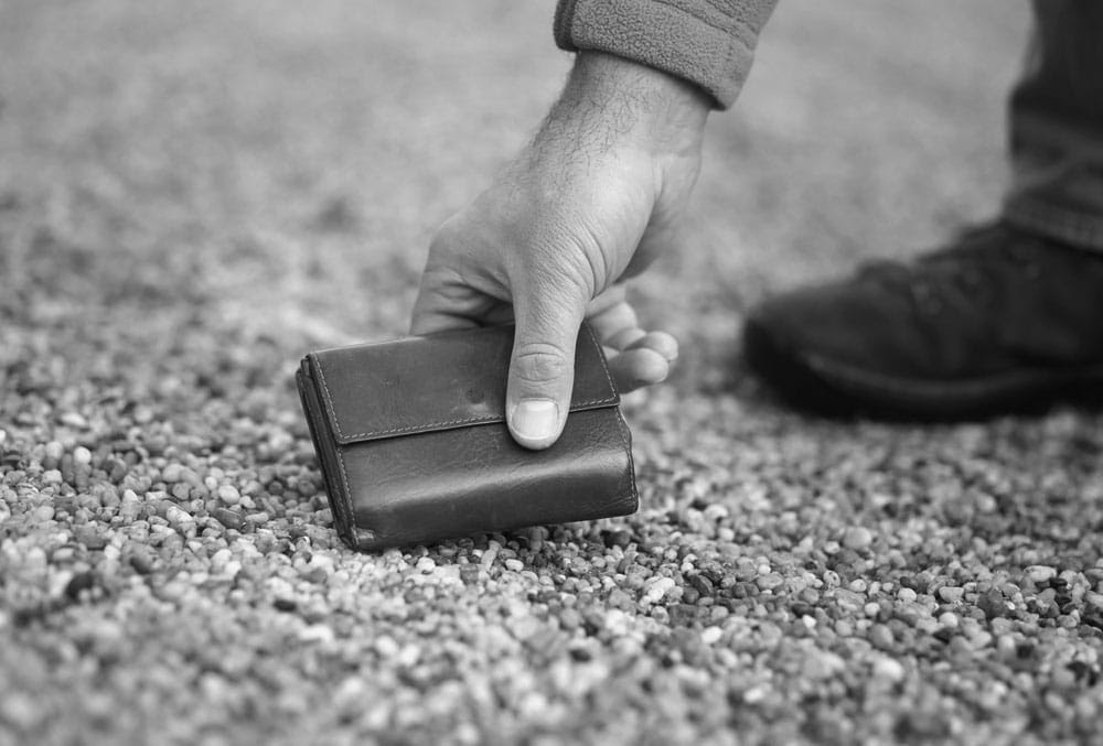 man picking wallet up off ground black white photo