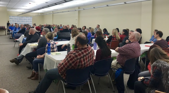 Wyoming Department of Education employees sit at tables filling a conference room during the all-staff meeting.