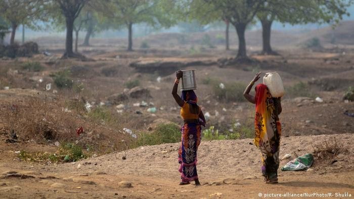 Duas mulheres indianas retornam após transportar água potável de um caminhão-tanque municipal durante um dia quente na vila de ShankarGarh, a cerca de 40 km de Allahabad, em 6 de junho de 2019. 