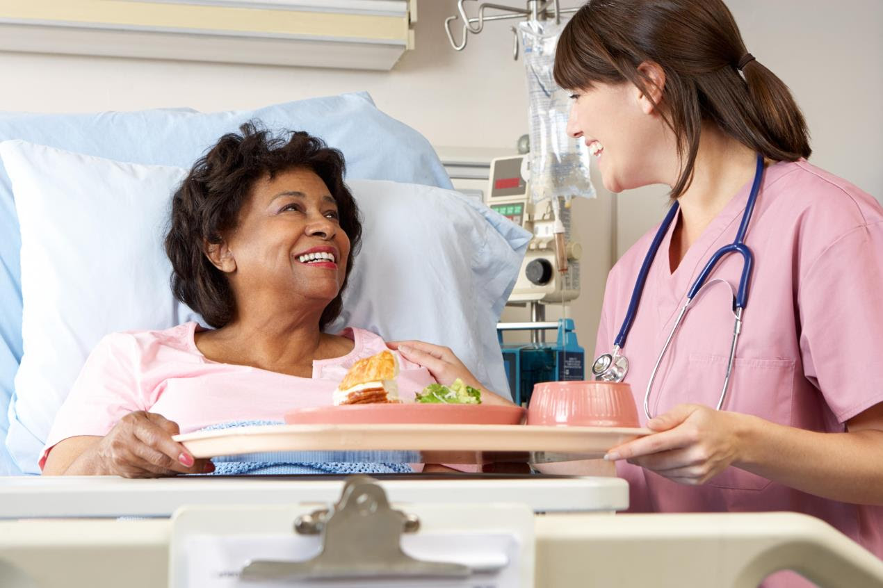 nurse giving patient food in hospital