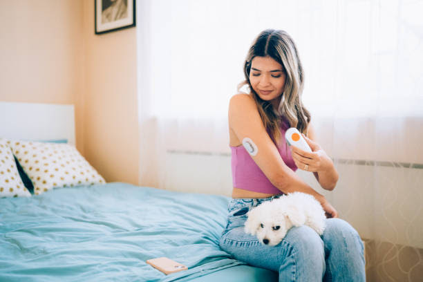 Day in the life of young woman with type 1 diabetes Young woman putting new sensor on the back of upper arm control blood sugar levels stock pictures, royalty-free photos & images