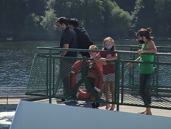 Photo of people wearing face coverings while on the outdoor deck of a ferry