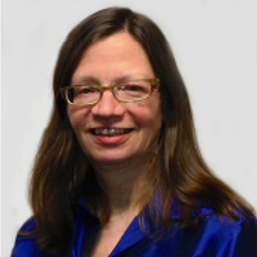 Image of a smiling bespectacled woman with long brown hair. She

is wearing a blue button up shirt.