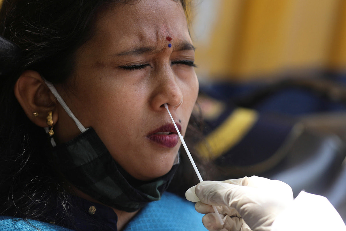 click for large image A health worker collects a swab sample from a woman during a rapid antigen testing campaign for the coronavirus disease (COVID-19), on a street in Mumbai, India, on 30 March 2021.