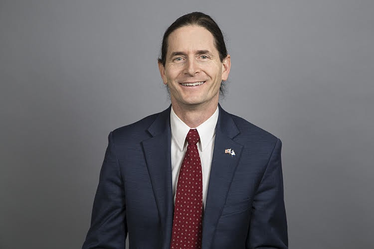 A person wearing a suit and tie smiling at the camera

Description automatically generated